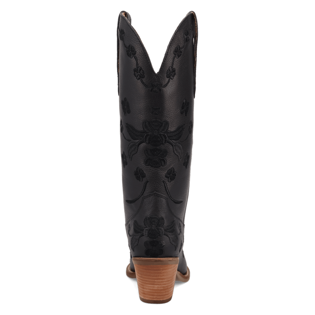 A single black leather cowboy boot shown from the back, featuring black floral debossed embroidery and a stacked brown wooden heel, set against a plain white background.