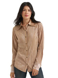 A woman modeling a long-sleeve button-up shirt with a vertical pleated texture in a metallic champagne beige color, paired with dark jeans against a light gray studio background.